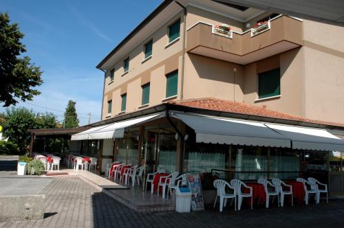 a building with tables and chairs in front of a building at Hotel Da Angela in Sedegliano