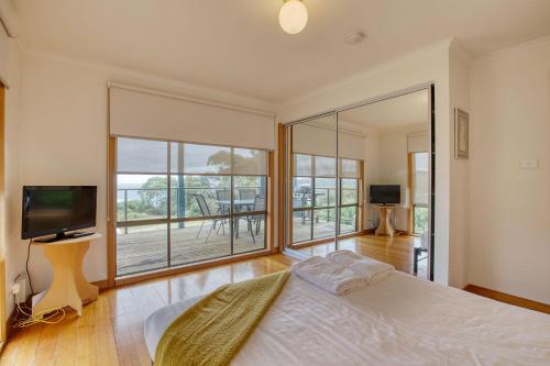1 dormitorio con cama y ventana grande en Lazy Wave Beach House, en Binalong Bay