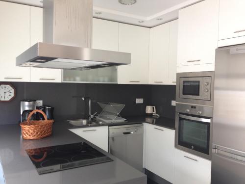 a kitchen with white cabinets and silver appliances at Casa Da Trigueira in Santa Eugénia