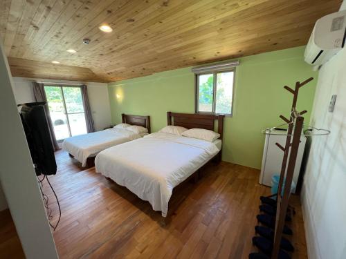 Habitación con 2 camas, paredes verdes y suelo de madera. en 樂樂茶民宿, en Yung-an-ts'un