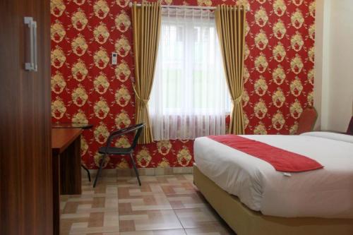 a hotel room with a bed and a desk and curtains at Edotel Manggala Syariah RedPartner in Sudimara