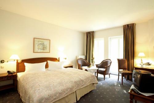 um quarto de hotel com uma cama e cadeiras e uma televisão em Freimühle Hotel-Restaurant em Girod