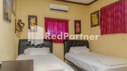 泗水的住宿－Vandhela Homestay Syariah Mitra RedDoorz，配有红色窗帘的客房内的两张床