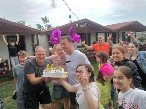 a group of people standing around a man holding a birthday cake at La 3 Casute in Nufăru
