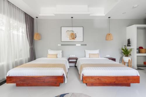 two beds in a room with white walls at La Bastide de Caro in Siem Reap
