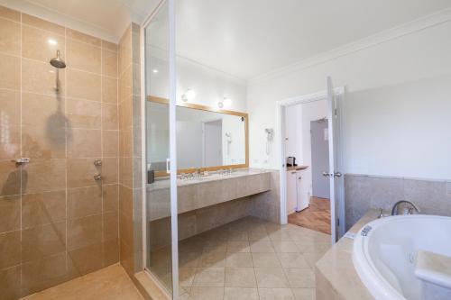 a bathroom with a tub, shower, and toilet at The Quarters Forresters Beach in Wamberal