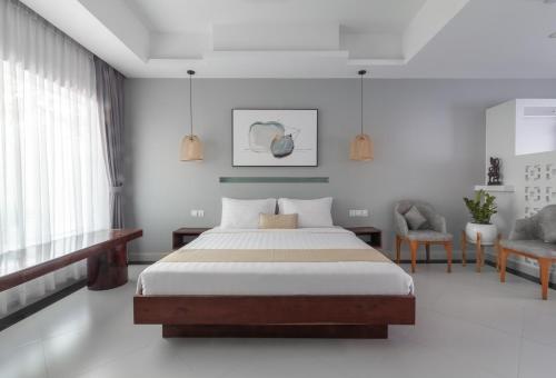 a bedroom with a bed and a desk and chairs at La Bastide de Caro in Siem Reap