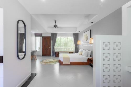a white bedroom with a bed and a window at La Bastide de Caro in Siem Reap