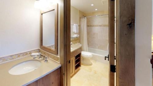 a bathroom with a sink and a toilet and a mirror at Slopeside 3 Bedroom Gold-rated Residence At Golden Peak Steps To Vail Village in Vail