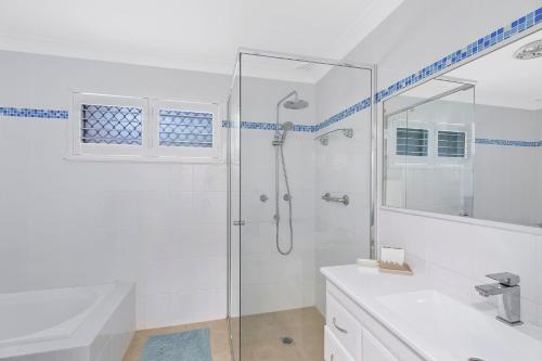 a white bathroom with a shower and a sink at Sandcastles in Budgewoi