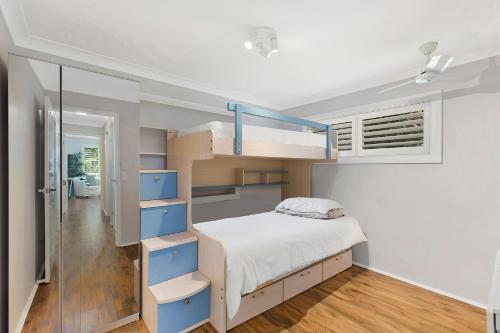 a small bedroom with a bunk bed and blue shelves at Sandcastles in Budgewoi