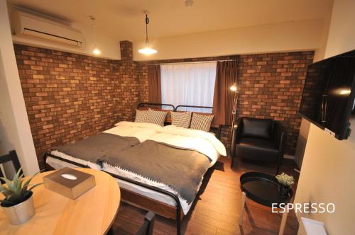 ein Schlafzimmer mit einem Bett und einer Ziegelwand in der Unterkunft Maison Milano Nakatsu Apartment in Osaka