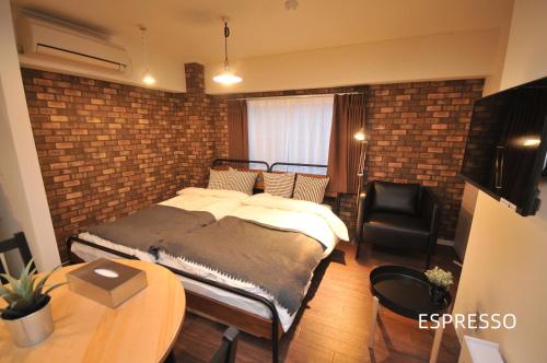 a bedroom with a bed and a brick wall at Maison Milano Nakatsu Apartment in Osaka