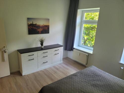 een slaapkamer met een wit dressoir en een raam bij Waldemar-Appartement in Rostock