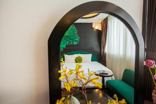 a hotel room with a bed and a green chair at Hanoi Center Silk Boutique Hotel & Travel in Hanoi