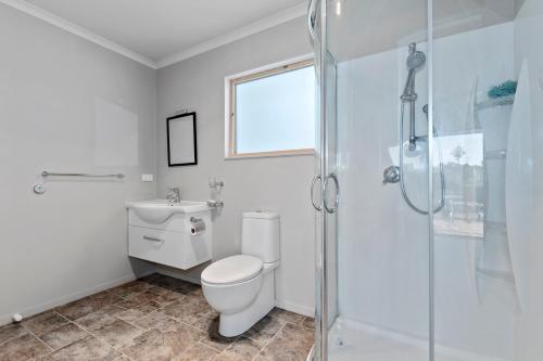 a bathroom with a toilet and a glass shower at Ruakaka River Retreat - Ruakaka Holiday Home in Ruakaka