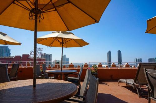 a table and chairs with umbrellas on a balcony at Gaslamp Plaza Suites in San Diego