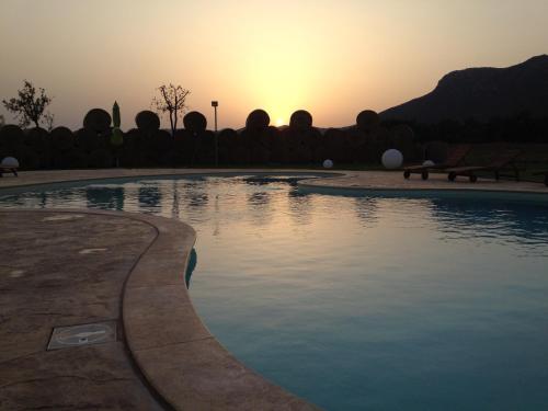 a swimming pool with the sunset in the background at Saludi&Trigu - Rural Apartments in Iglesias