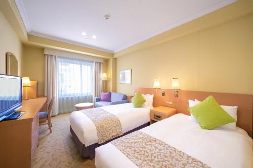 a hotel room with two beds and a television at Namba Oriental Hotel in Osaka