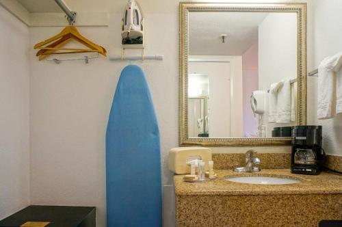 a bathroom with a blue surfboard next to a sink at Howard Johnson by Wyndham San Diego Hotel Circle in San Diego