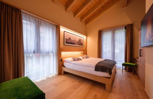 a bedroom with a bed and a large window at Hotel Tannenhof in Zermatt