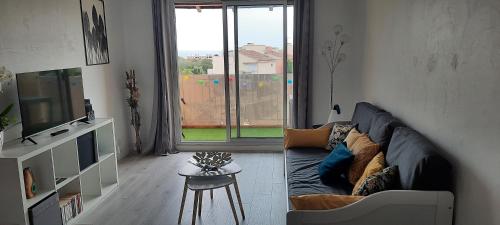 un salon avec un canapé et une grande fenêtre dans l'établissement Superbe appartement avec balcon vue mer !, à Carqueiranne