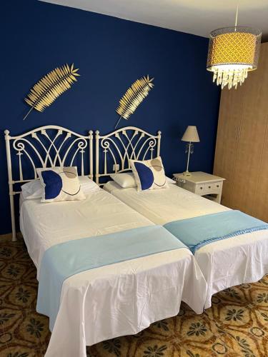 2 letti in una camera da letto con parete blu di CORNELIA'S HOME 1B primera línea de playa a Los Cristianos