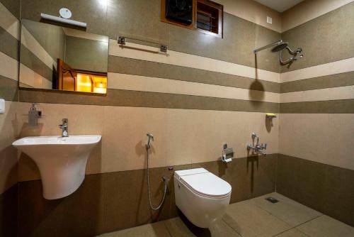 a bathroom with a sink and a toilet and a mirror at Stephen's Legacy in Vattavada
