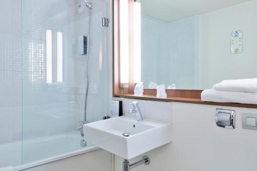 a white bathroom with a sink and a shower at Campanile Lyon Sud Feyzin in Feyzin
