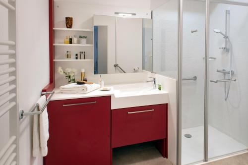 Saint-Aubin-lès-ElbeufにあるDOMITYS LA ROZE DE SEINEのバスルーム(赤と白の洗面台、シャワー付)