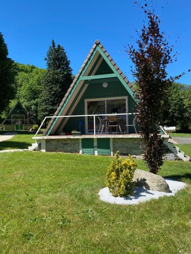 a house with a green roof with a tree at Hotel Le Chalet in Sainte-Marie-de-Campan