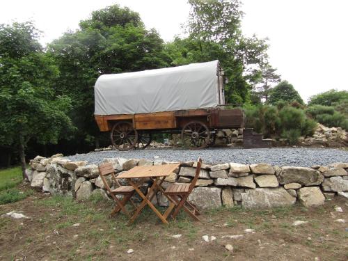 a truck parked next to a table and a stone wall at La Bergerie du Plateau in Cros-de-Géorand