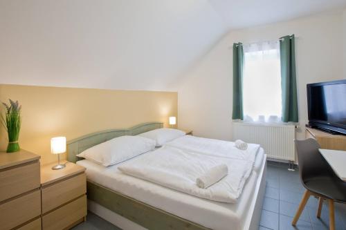 a bedroom with a white bed and a television at Šindlovská krčma in České Budějovice