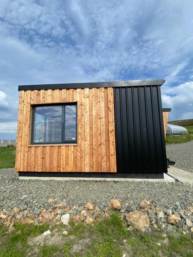 a small house with a wooden wall and a window at Unique luxurious cabin on sea view working croft in Garrabost