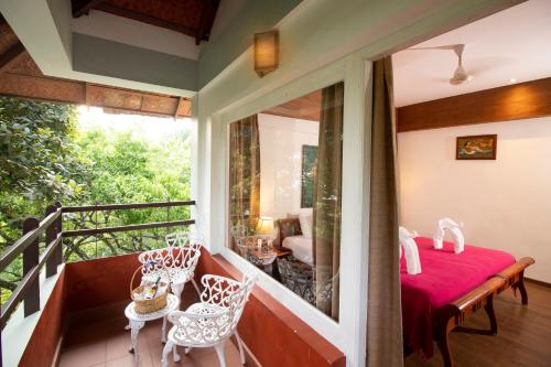 a room with a balcony with a red table and chairs at Blackberry Hills Munnar Nature Resort & Spa in Munnar