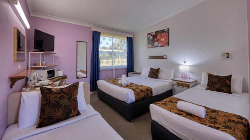 a hotel room with two beds and a couch at BUSHMANS RETREAT MOTOR INN in Gundagai