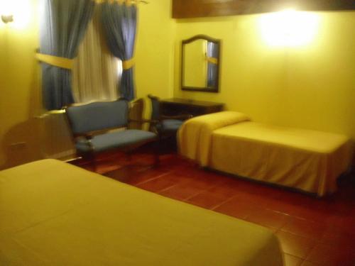Pokój z 2 łóżkami, krzesłem i lustrem w obiekcie Hostal La Mancha w mieście Tarazona de la Mancha