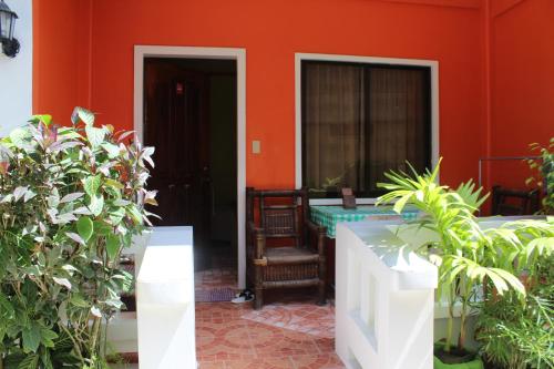 a patio with orange walls and a table and chairs at M&E Guesthouse in Boracay