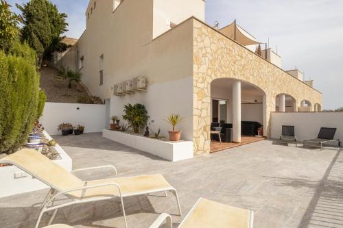 an outdoor patio with chairs and a building at Casa Curumbico in Almuñécar