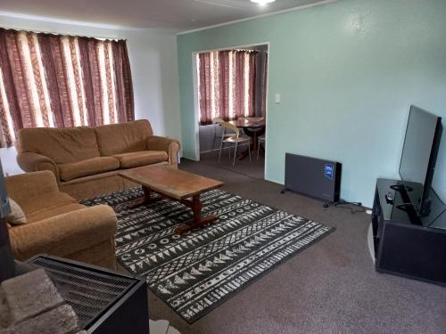 uma sala de estar com um sofá, uma mesa e uma televisão em Mount Budget Accommodation em Tauranga