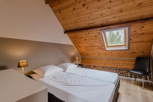 a bedroom with a bed and a window and a chair at De Groene Hoeve in Brakel