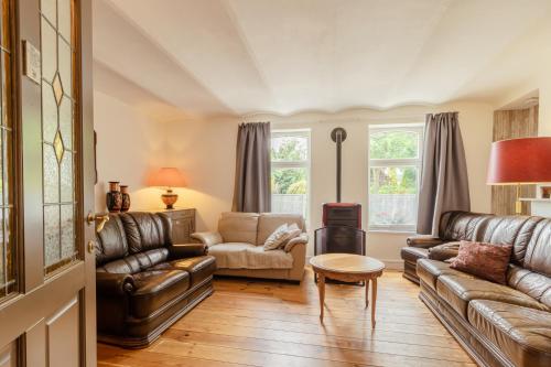 a living room with leather furniture and a table at De Groene Hoeve in Brakel