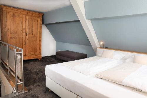a bedroom with a white bed and a wooden cabinet at Landidyll Hotel Klostermühle in Münchweiler an der Alsenz