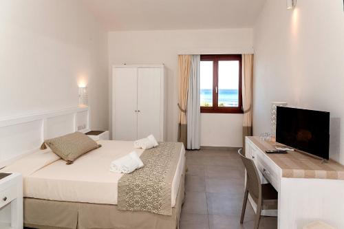 a bedroom with a bed and a desk and a television at Stella Marina Budoni in Budoni