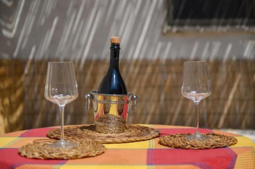 a bottle of wine in a bucket on a table with two glasses at Salento incantevole alloggio fronte mare in Marittima