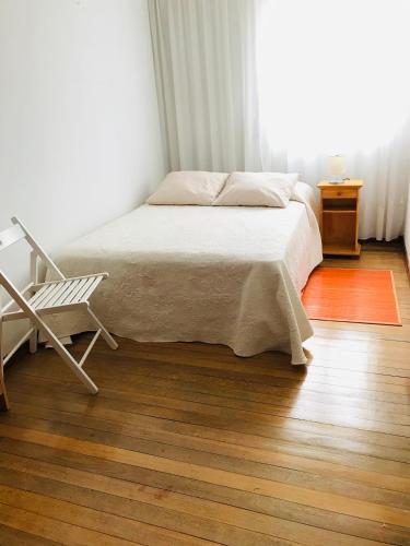 a bedroom with a bed and a chair on a wooden floor at Casa CHORIMA in Arzúa