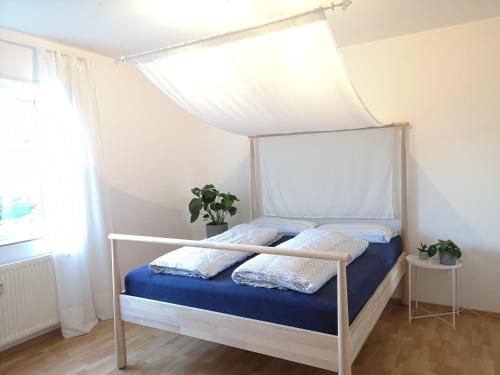 Una cama blanca con dosel en un dormitorio en Ferienwohnung Sonnenberg an der Weinstraße, en Leinsweiler