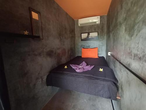 a small bedroom with a bed with a purple flower on it at Keramas Surf Hostel in Keramas
