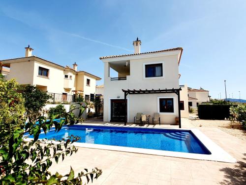 eine Villa mit einem Swimmingpool vor einem Haus in der Unterkunft Villa Jacaranda Altaona Golf in Murcia