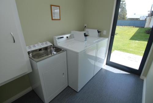 a white kitchen with a sink and a washing machine at High Peaks Hotel in Fox Glacier